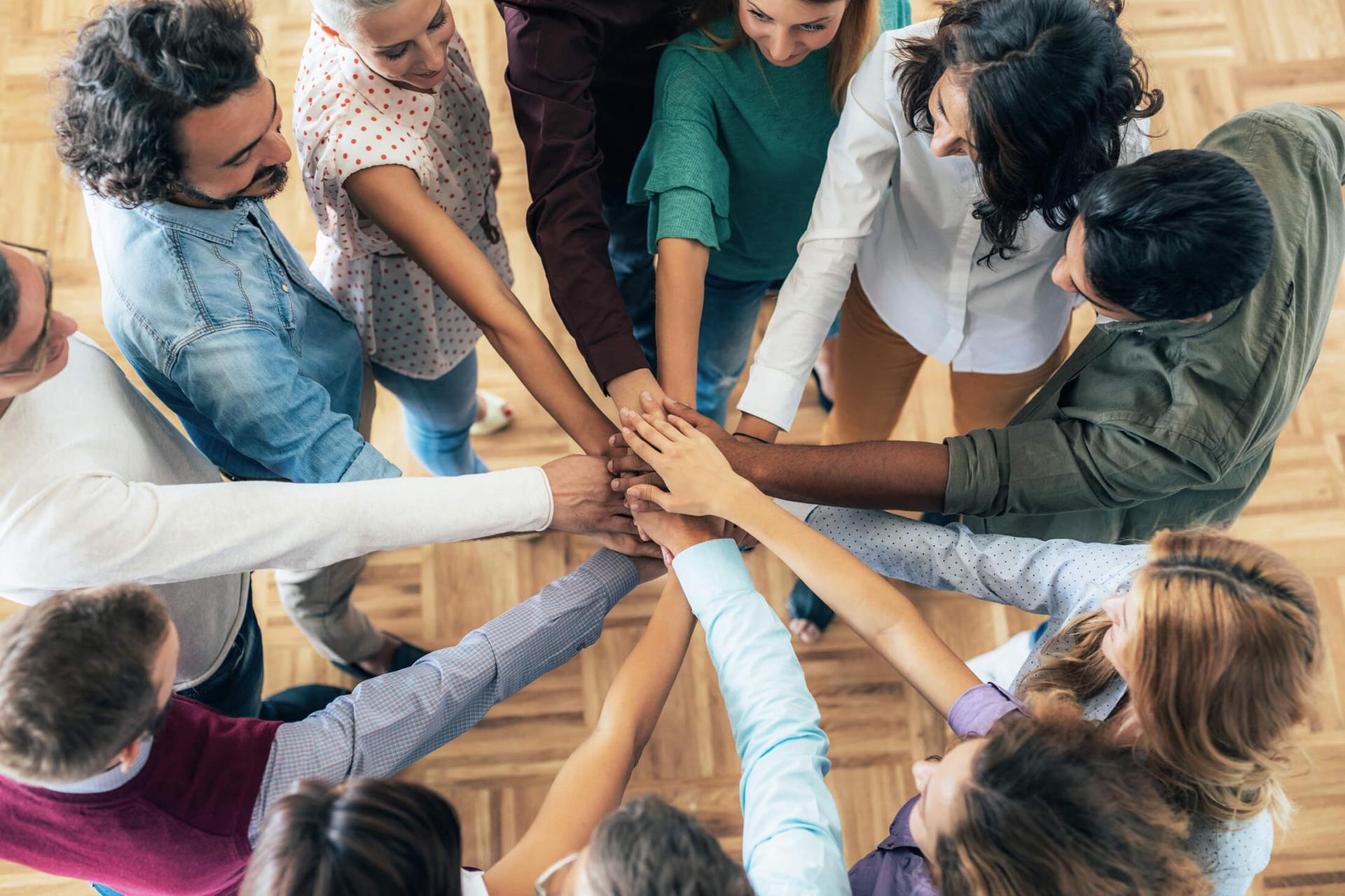 Colleagues all put their hands in the middle of a circle