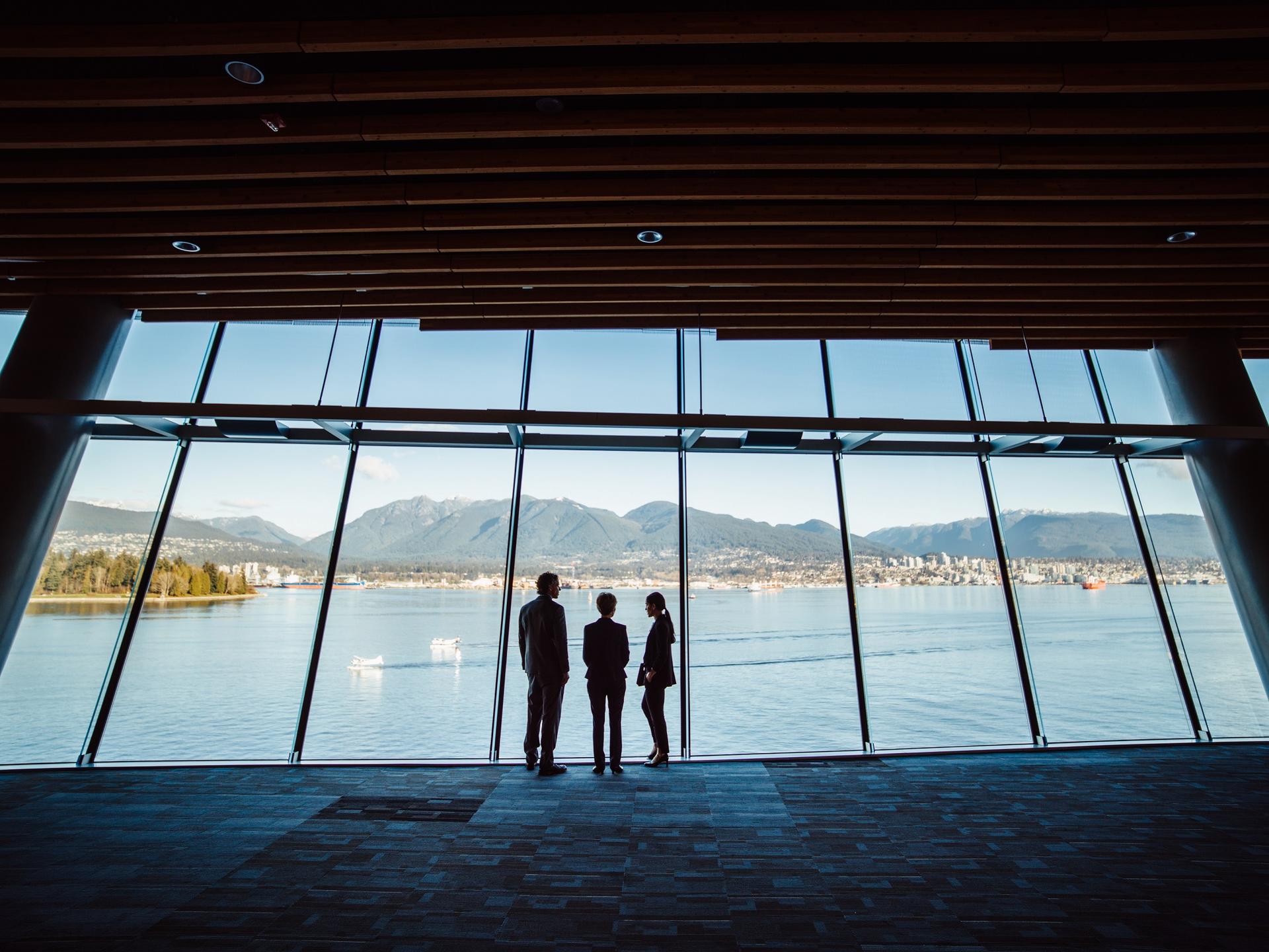 Three people looking out at a glass with views of Vancouver's mountains