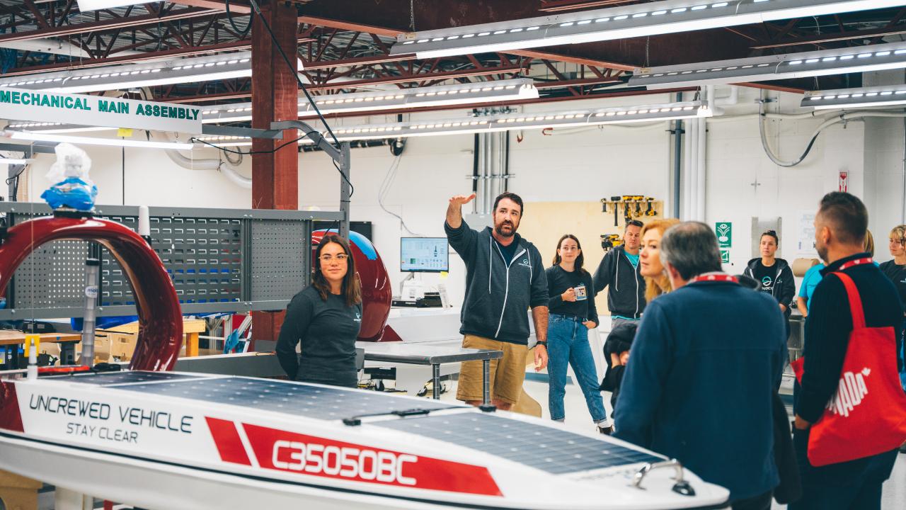 Expert explaining the uncrewed surface vehicle to group in facility