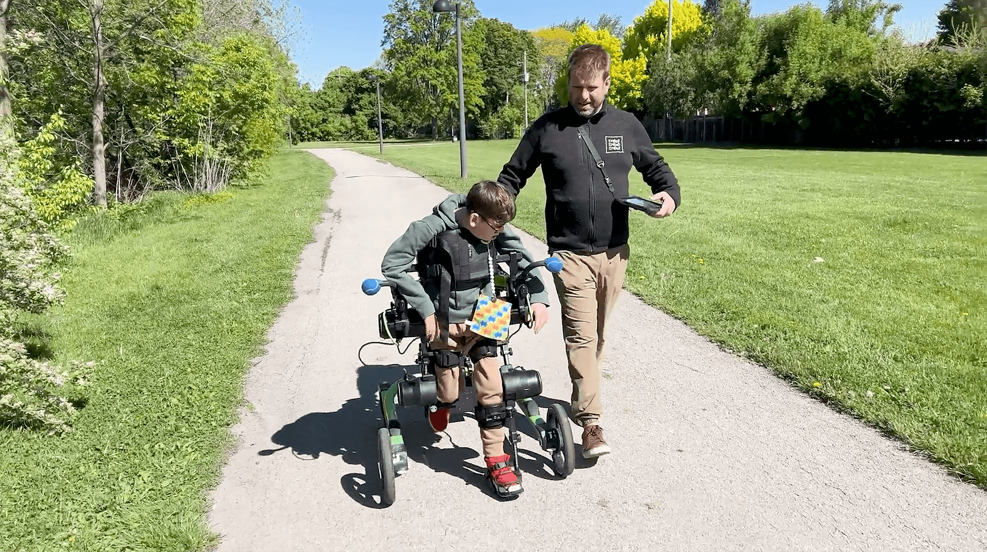 A man walking with his son who is using a Trexo exoskeleton to walk.